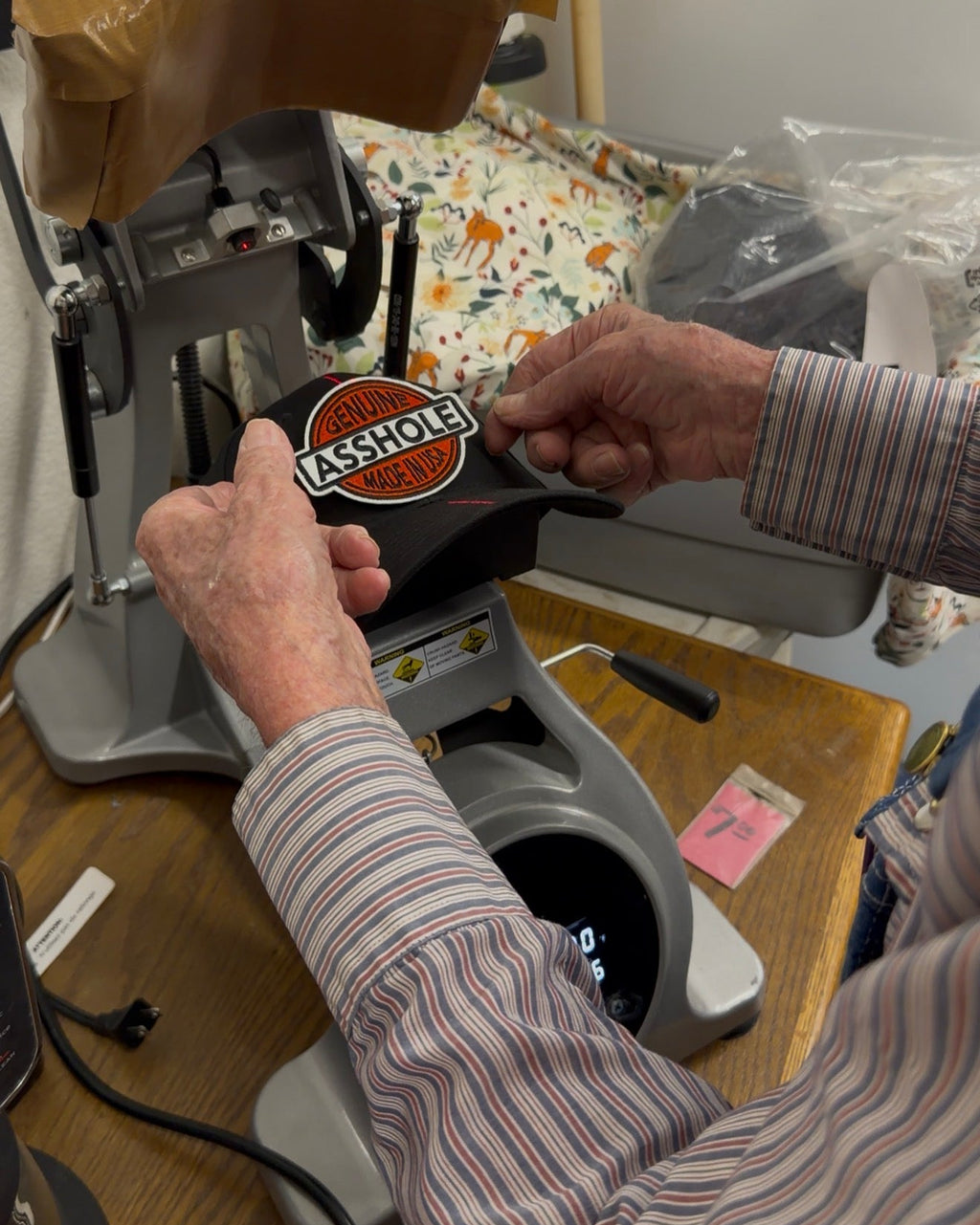 Person using a heat press machine with a patch being pressed on a hat